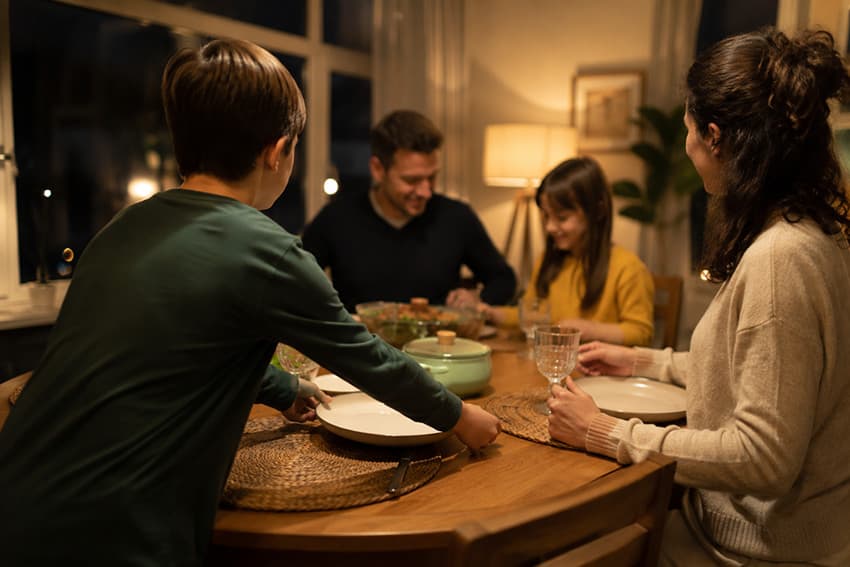 Aile sofrasında sohbet eden anne baba ve çocuk, ödevsiz eğitim modelinde aile zamanı